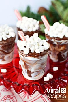 three cups filled with chocolate and marshmallows on top of a red tray