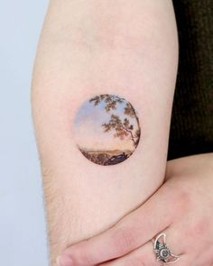 a person with a small circular tattoo on their arm