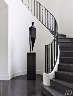 a black and white stair case next to a metal sculpture in the corner of a room