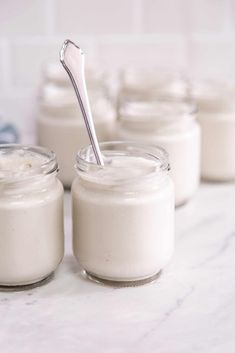 there are many small glass jars with some food in them on the table and one has a spoon sticking out of it