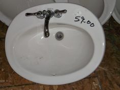 a white sink sitting on top of a wooden floor next to two urinals