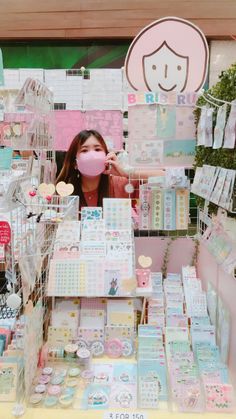 a woman standing in front of a store filled with lots of cards and stickers