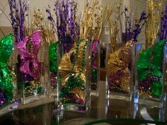 several vases filled with purple and green flowers on top of a round glass table