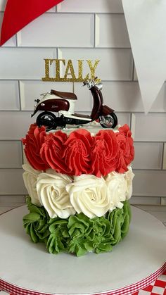 a birthday cake decorated with flowers and a motorbike on the top that says italy