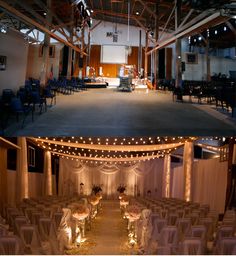 the inside and outside of a building with lights strung from it's ceiling, decorated for a wedding ceremony