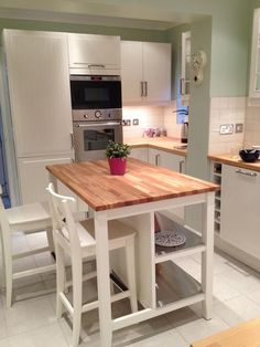 a kitchen with white cabinets and an island in front of a stove top oven next to a sink