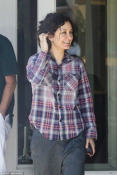 a woman walking down the street talking on her cell phone while wearing a plaid shirt