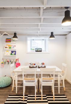 a white table and chairs in a room with black and white rugs on the floor