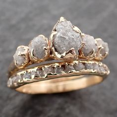 two gold rings with white diamonds on them sitting on a black surface in front of a gray background