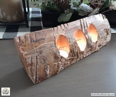 a wooden candle holder with four lit candles in it on a table next to some pine cones