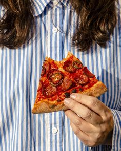 a person holding a slice of pizza with pepperoni and cheese on it in their hands