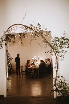 a group of people sitting at a table in a room with vines on the wall