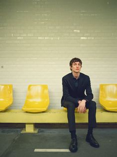 a young man sitting on a yellow bench