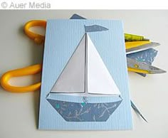 a card with a paper boat on it and scissors next to the cut out sailboat