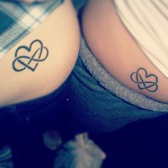 two women with tattoos on their stomachs, one has an intertwined heart tattoo