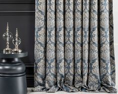 a black table with a silver lamp and curtain