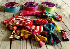 several different types of hair bows on a wooden table with two small tins in the background