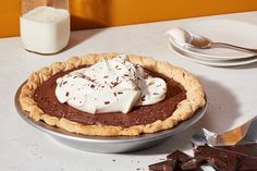 a chocolate pie with marshmallows and whipped cream on top sits on a table