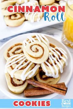 cinnamon roll cookies on a white plate with cinnamon sticks and orange juice in the background