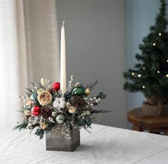 a christmas centerpiece with candles and flowers on a table in front of a window