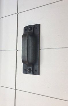 a black door handle on a white tile wall