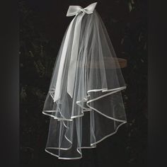 a white veil hanging from the side of a chair with a bow on it's back