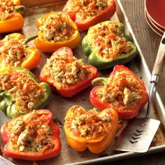 several stuffed peppers on a baking sheet with a spatula