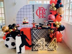 a table topped with balloons and cake next to a soccer themed wall mounted on the wall