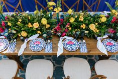 the table is set with plates and flowers on it, along with other place settings