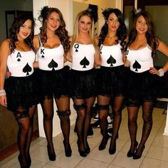 four beautiful women dressed up in costumes posing for a photo with cards on their chest