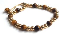 "Tigers Eye Bracelet This modern and stunning Shamballa bracelet is made with an adjustable chain brass 18k gold plated and beaded with an 8mm genuine tiger eye beads, and gold-filled balls. It is a nice piece for everyday use and combines with any casual outfit. This is a perfect Birthday, graduation, Christmas or Mothers day gift. The bracelet is adjustable to any wrist size with a comfortable sliding clasp closure. It can be adjusted from 6\" to 9\" inches approximately. Each item is carefull Adjustable Yellow Gold Plated Bracelets, Adjustable Gold-plated Bracelets, Adjustable Gold-plated Bracelets With Round Beads, Adjustable Gold Rosary Bracelet With Jubilee Detail, Adjustable Gold Plated Beaded Bracelets With Round Beads, Adjustable Gold-tone Luxury Bracelets, Adjustable Gold Rosary Bracelet, Adjustable Yellow Gold Rosary Bracelet, Adjustable Yellow Gold Beaded Bracelet