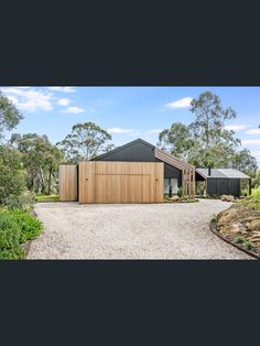 the house is surrounded by trees and gravel