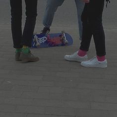 three people standing next to each other with their skateboards on the ground in front of them