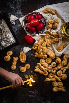 a person lighting candles in front of some pretzels and other foods on a table