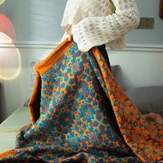 a woman is holding an orange and blue blanket