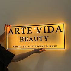 a woman holding up a sign that says arte vida beauty where beauty begins within