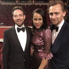 two men and a woman standing next to each other in front of an empty stage