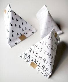 two folded paper christmas trees sitting on top of a white table next to each other