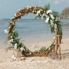 a wedding arch with flowers and candles on the beach