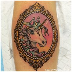 a tattoo with an image of a unicorn in a frame on the side of someone's leg