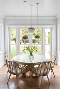 a dining room table surrounded by chairs and windows