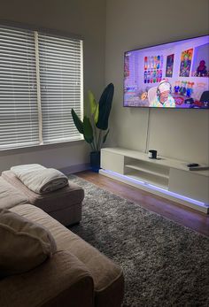 a flat screen tv sitting on top of a white shelf in a living room next to a window