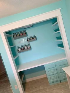 a white desk with shelves on the wall and drawers below it in a blue room