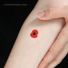 a woman's arm with a small red poppy tattoo on the left side of her arm