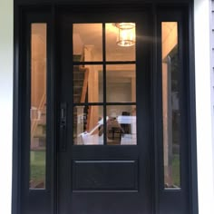 a black front door with glass panels and a light fixture on the side walk way