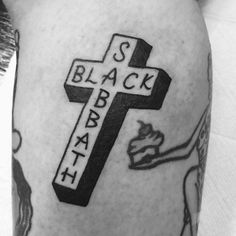 black and white photo of a cross tattoo on someone's right leg, with the word black bake written across it