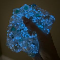 a hand is holding a glowing object with blue flowers on the top and bottom of it