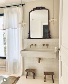 a bathroom with a sink, mirror and stools in front of the tub area