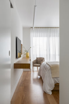 a bedroom with white walls and wooden floors, along with a bed that has a beige blanket on it