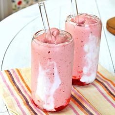 two glasses filled with food sitting on top of a striped table cloth next to each other